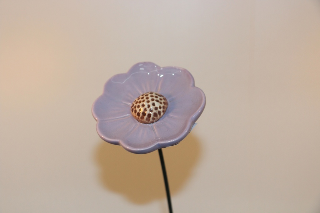Flor decorativa em cerâmica lilás com centro pontilhado e haste metálica