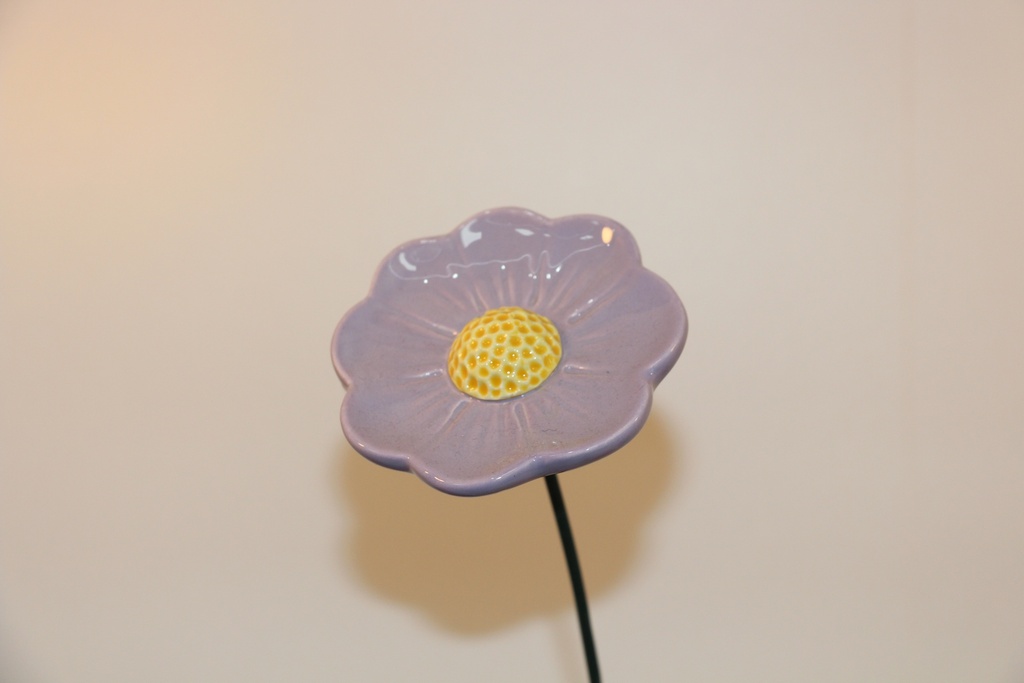 Flor decorativa em cerâmica lilás com centro amarelo e haste metálica