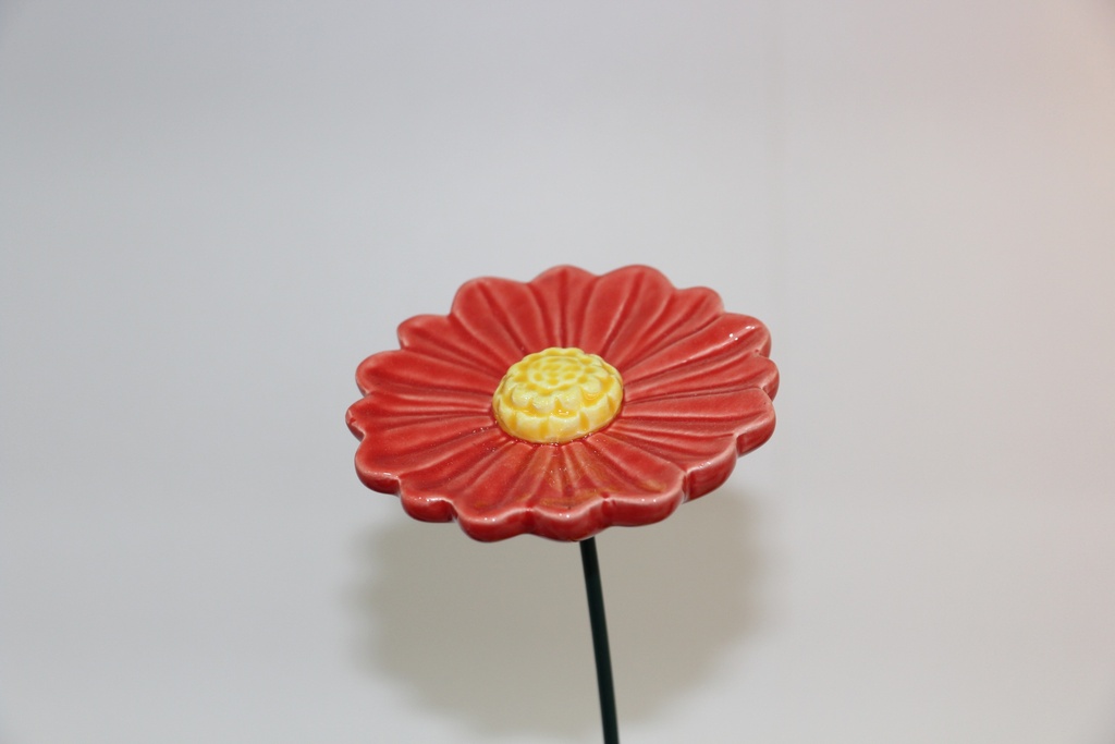 Flor decorativa em cerâmica vermelha com centro em espiral e haste metálica
