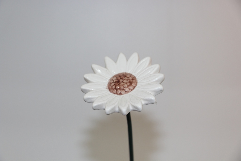 Flor decorativa em cerâmica branca com centro castanho e haste metálica