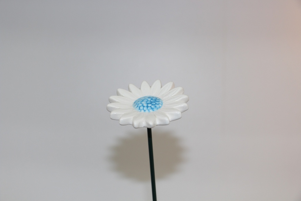 Flor decorativa em cerâmica branca com centro azul e haste metálica