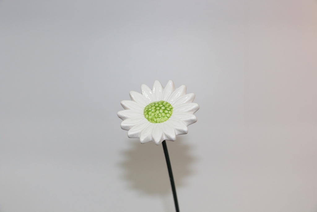 Flor decorativa em cerâmica branca com centro verde e haste metálica