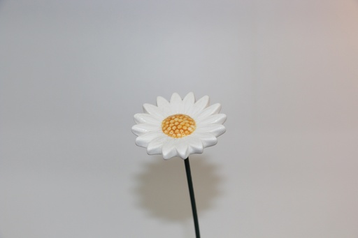Flor decorativa em cerâmica branca com centro amarelo e haste metálica